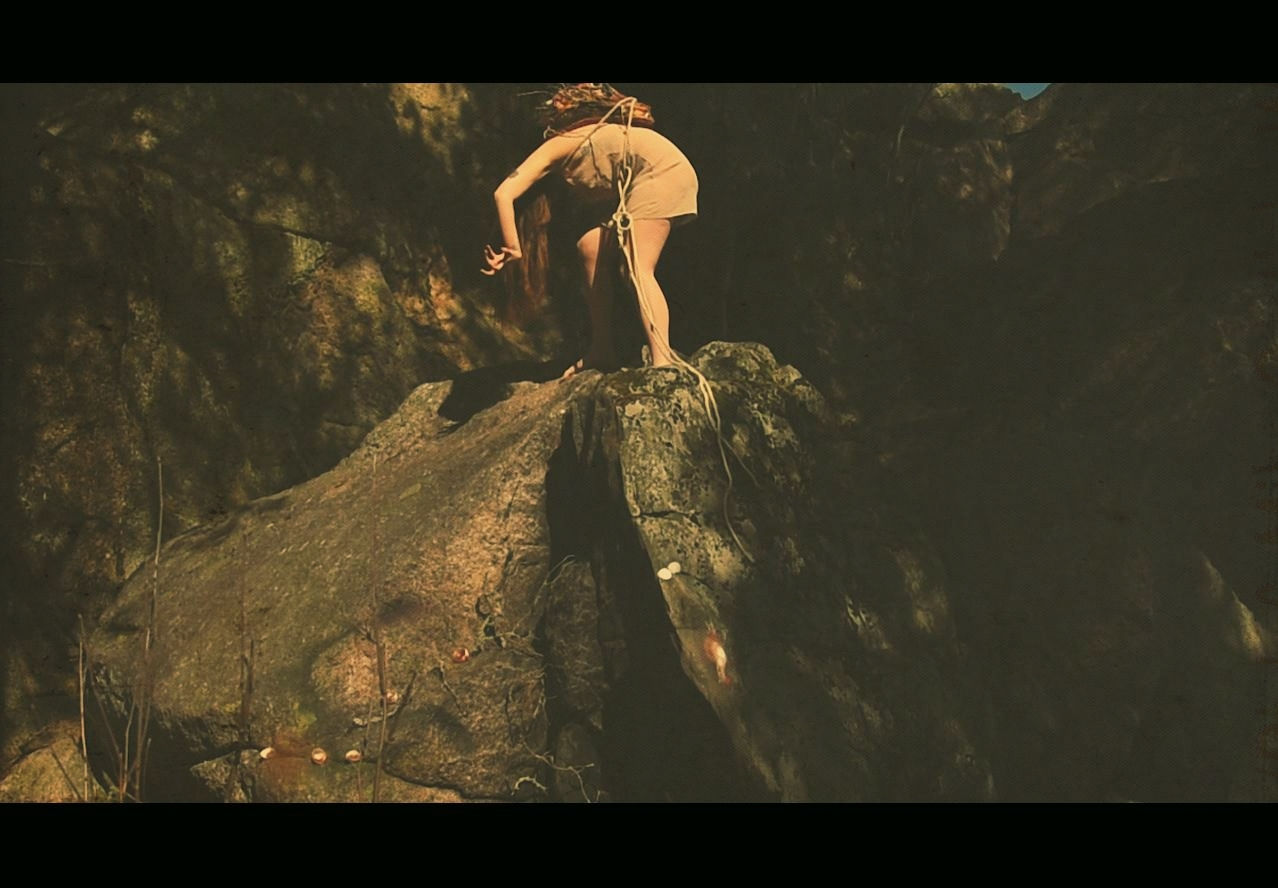 REPULSIVE BUT DELICIOUS. Tereza Holubová. Still. A figure crouches over at the top of a rock face.