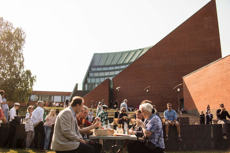 People sitting outside around a table in front of the Otaniemi main building