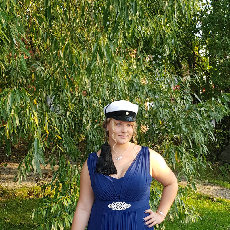 Jonna in a ballgown in the park wearing a Teekkari cap