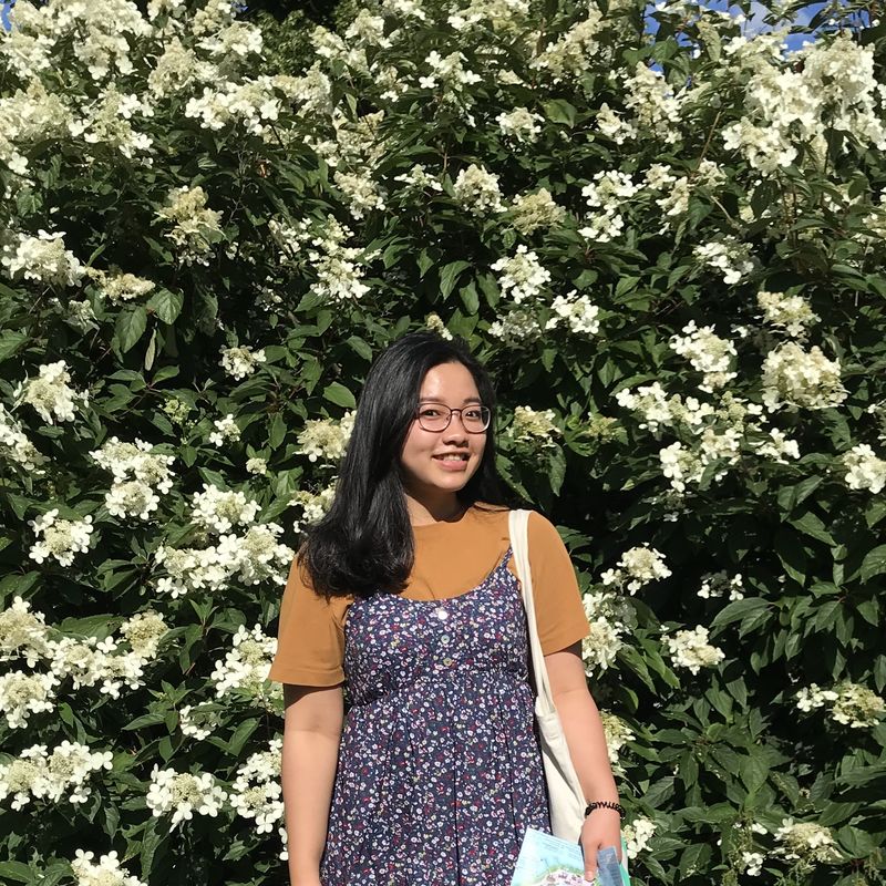 Linh standing in front of a flower wall smiling