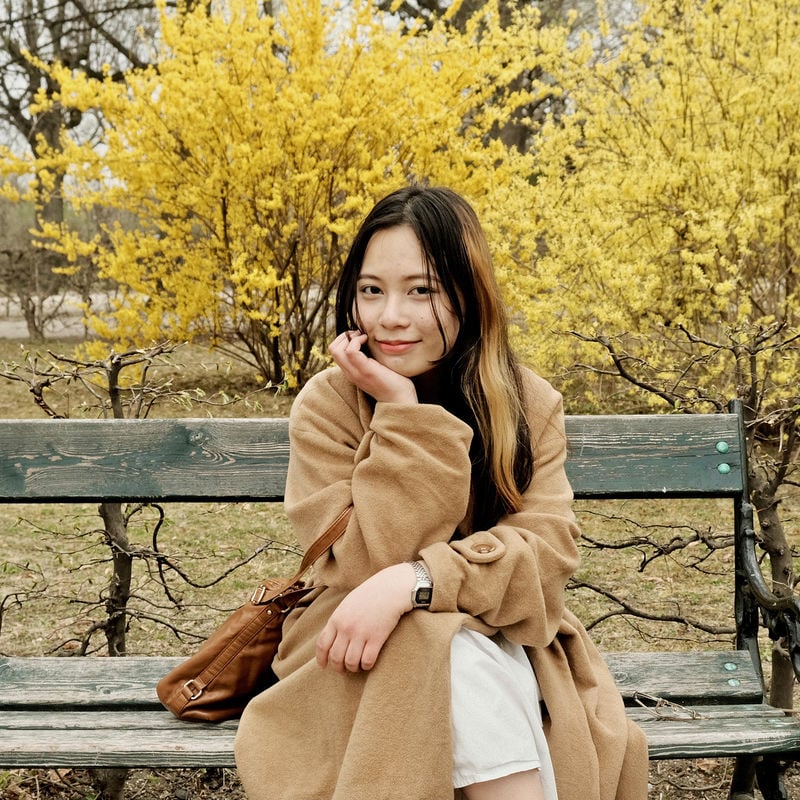 BScBA student Ly sitting on a park bench in autumn